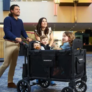Eine lächelnde Familie mit drei Kindern nutzt den WonderFold W4 Luxe Pro Kinderwagen 4-Sitzer Jet Schwarz in einem modern gestalteten Innenbereich.