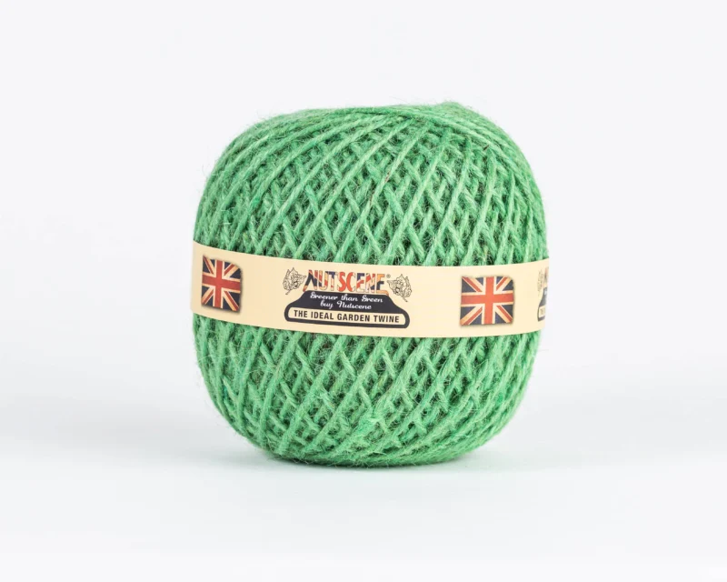 Ein Knäuel grünes „Nutscene | Heritage Jutegarn“ in der Farbe „Peapod“, 130 m, von Nutscene Twines Ltd, mit einem beigen Etikett, auf dem zwei britische Flaggen und der Schriftzug „Nutscene The Ideal Garden Twine“ vor weißem Hintergrund abgebildet sind.