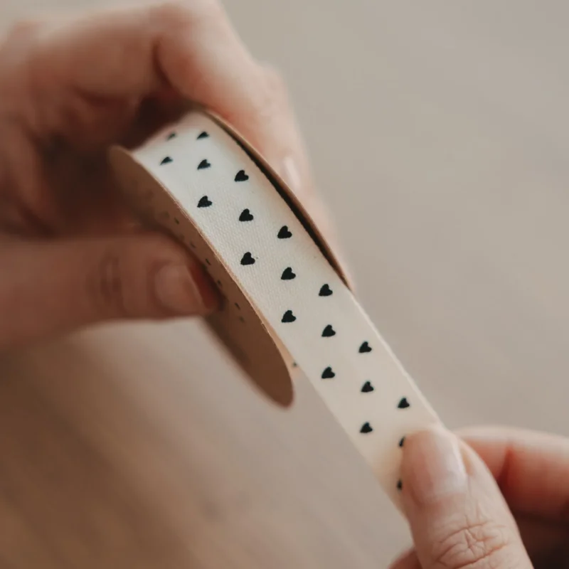 Geschenkband cremefarben mit kleinen schwarzen Herzen, Detailansicht der bedruckten Kante